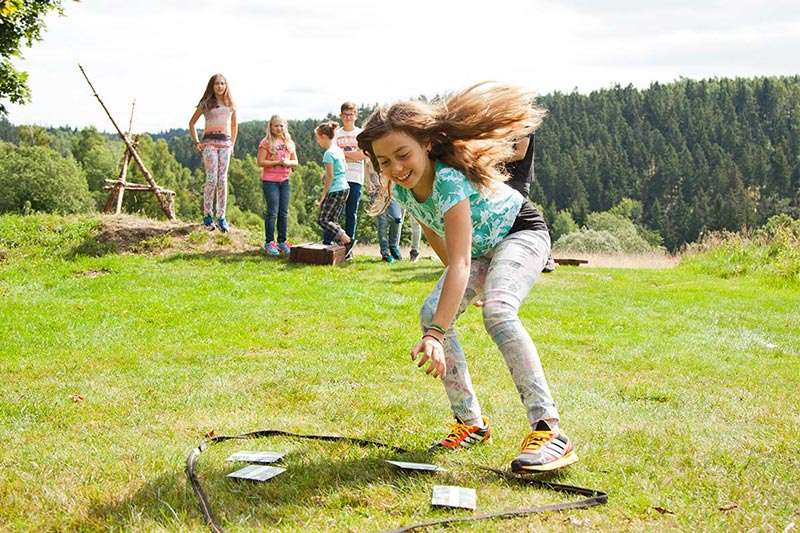 Schülerinnen und Schüler bei einem Team- und Bewegungsspiel auf einer Wiese am Waldrand im Harz.